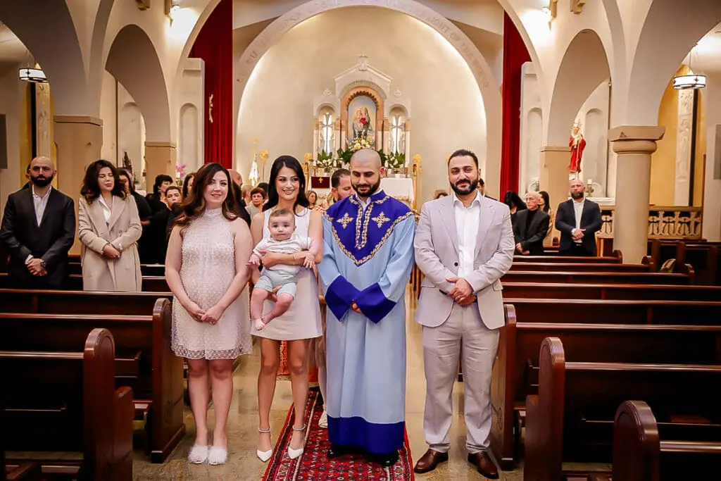 Smiling group at a church baptism, baby held front and center