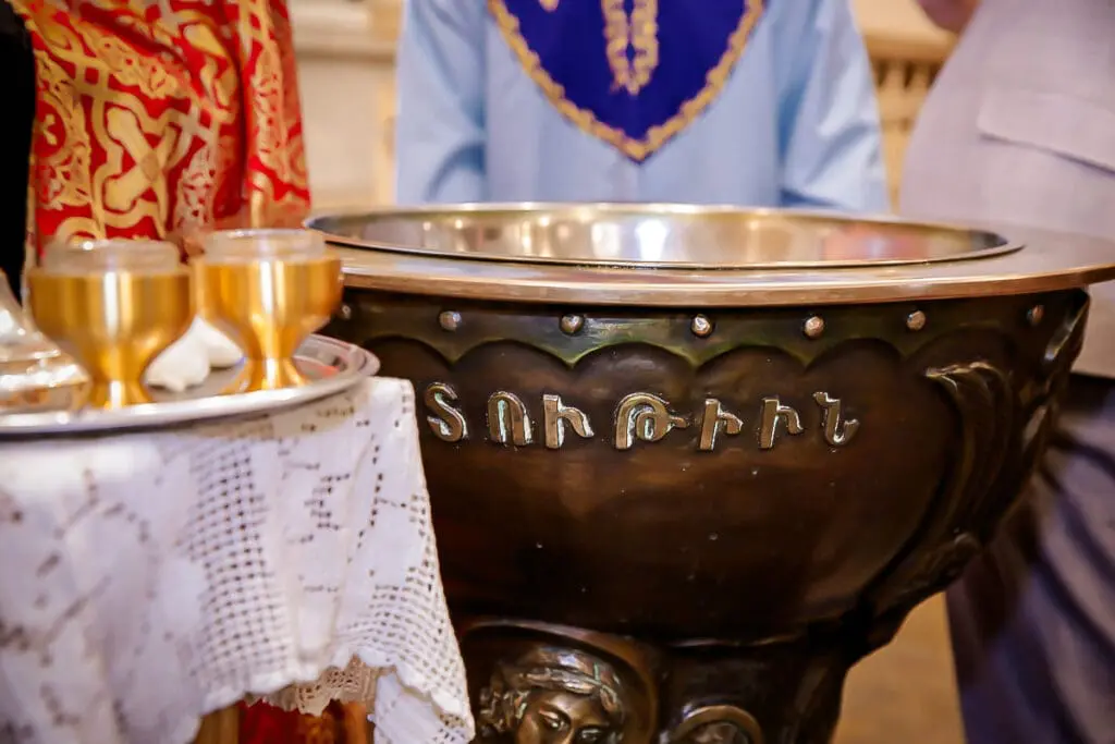 Close-up of an ornate baptismal font with Armenian script and gold chalices