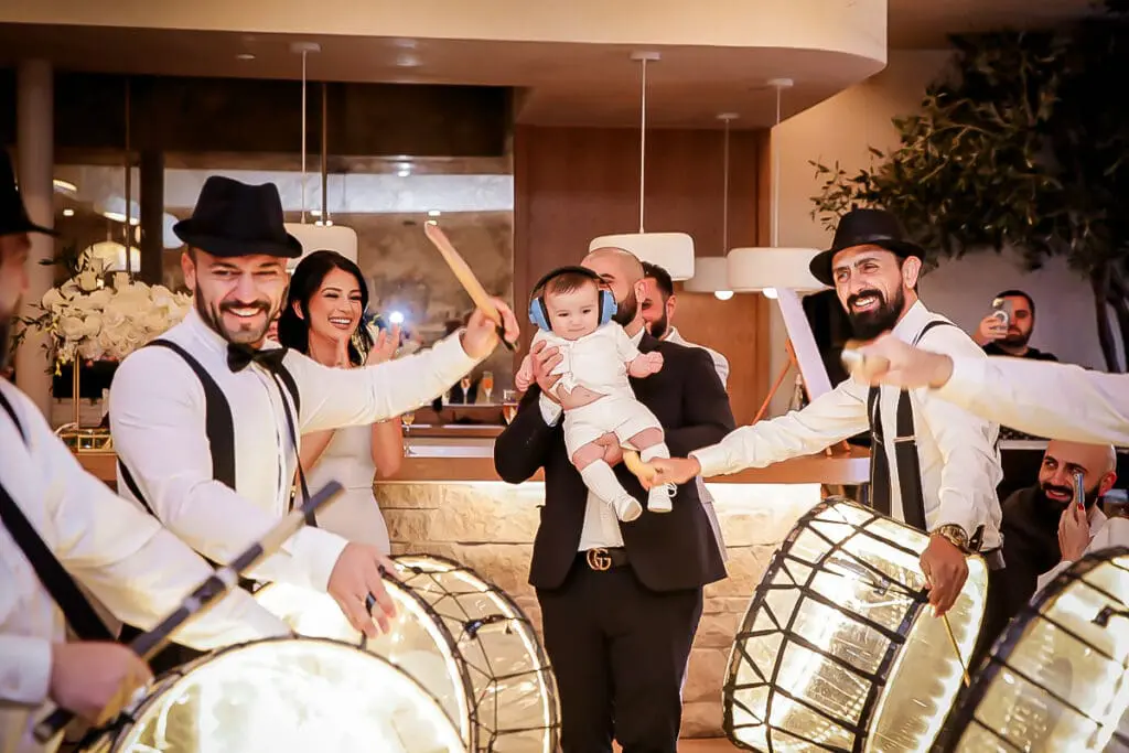 Happy celebration with glowing drums and a baby in earmuffs held high.