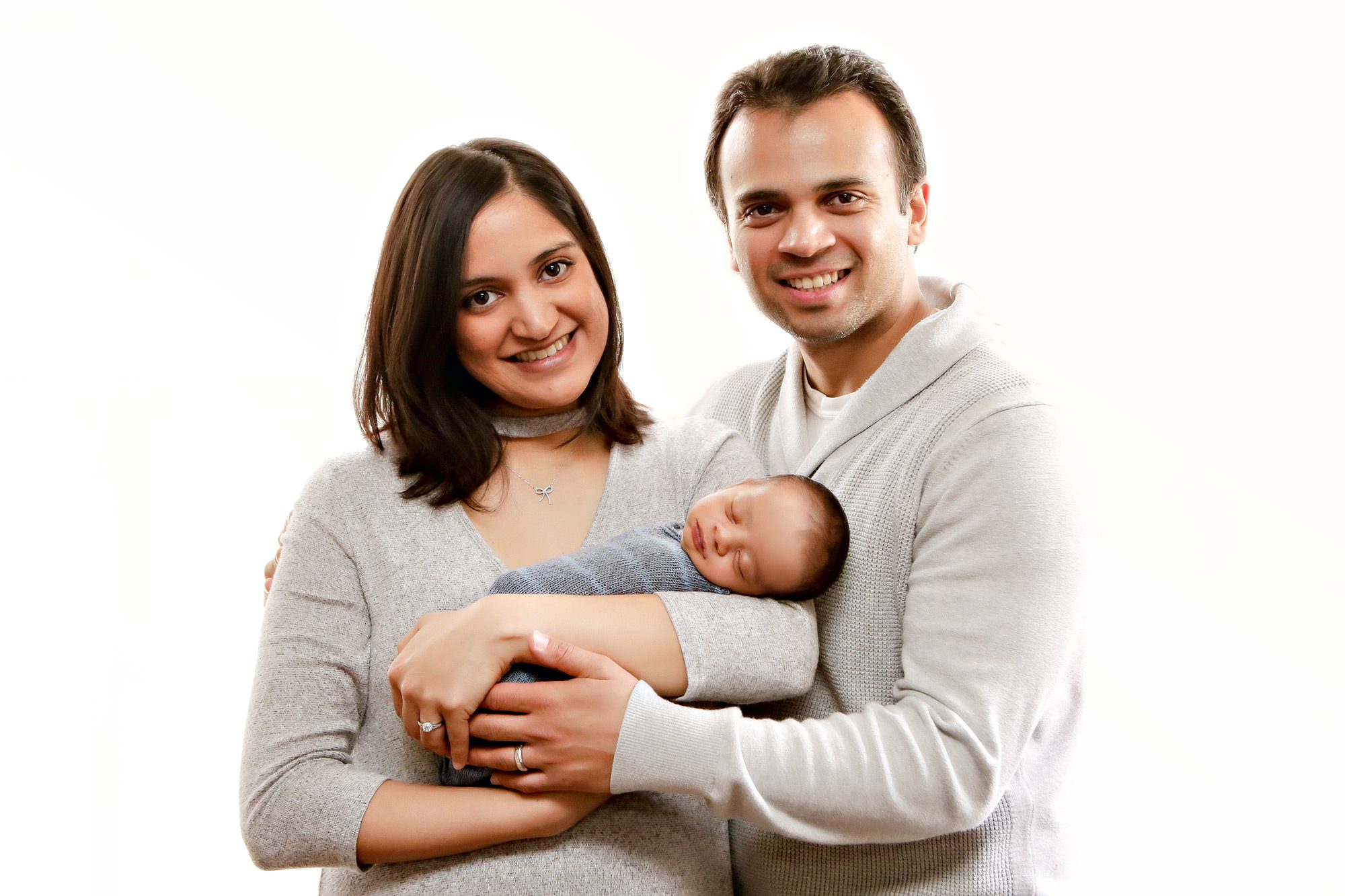 Family holding newborn in cozy setting.