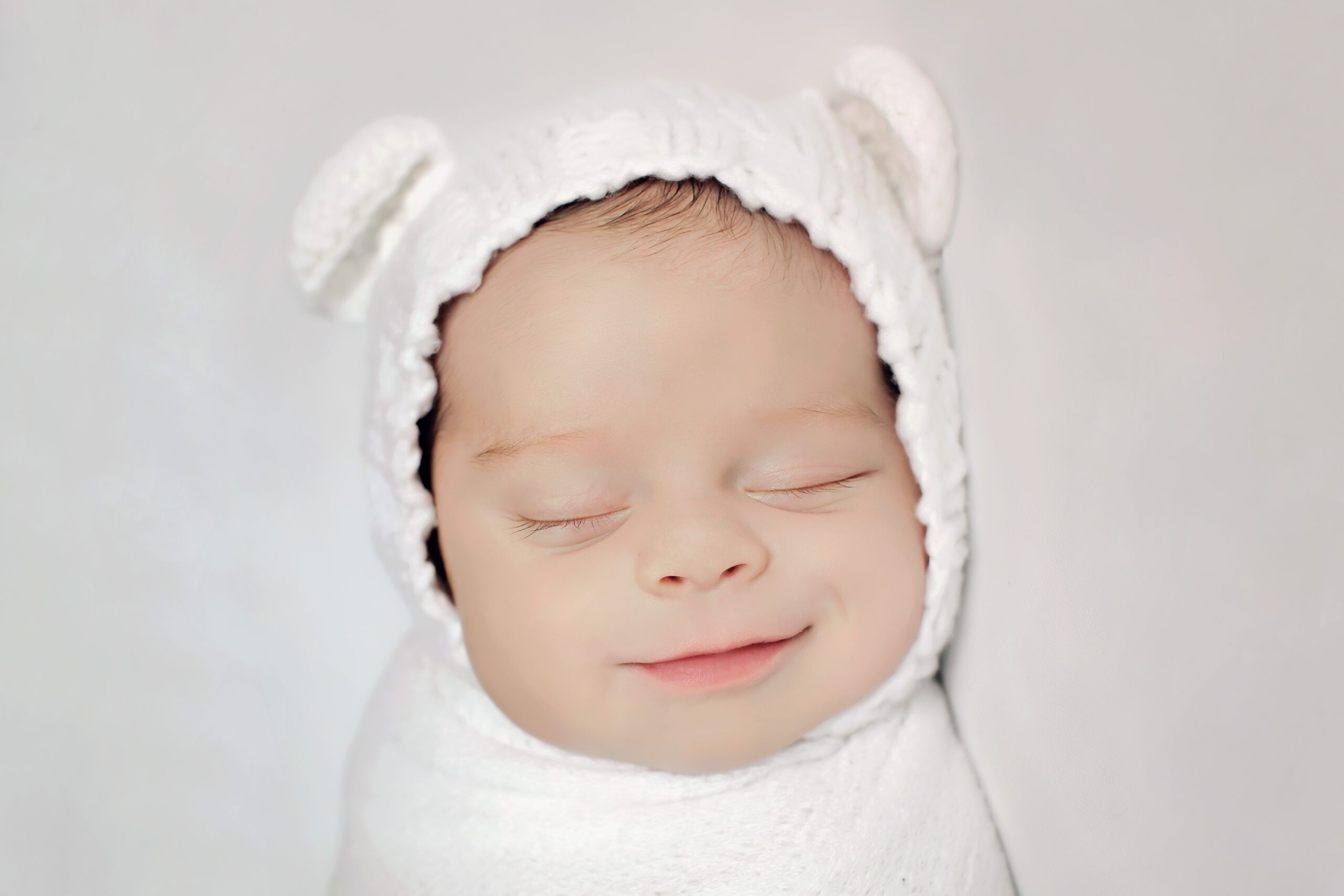 Newborn wrapped in bear-themed blanket.