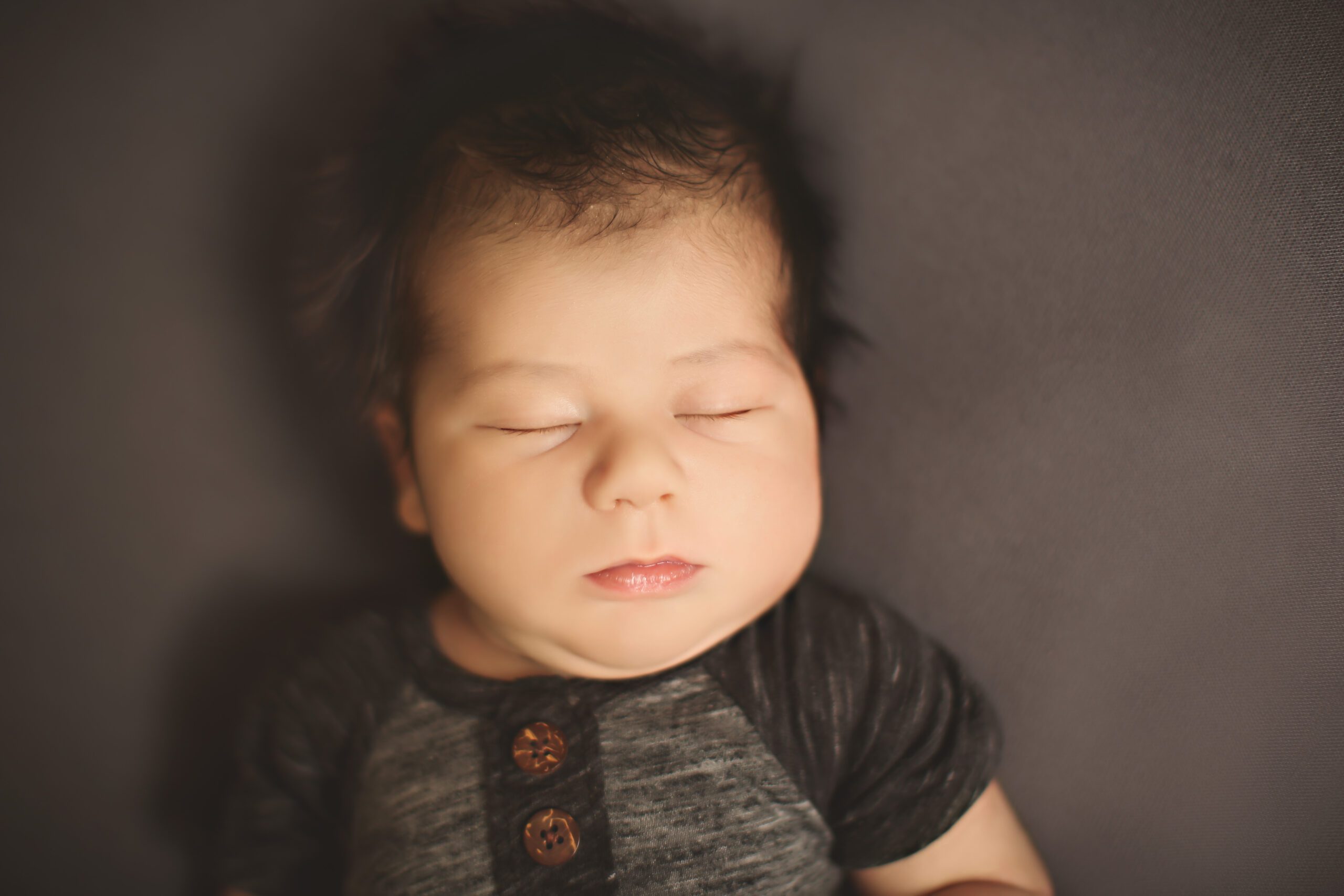 Newborn baby lying on dark background.