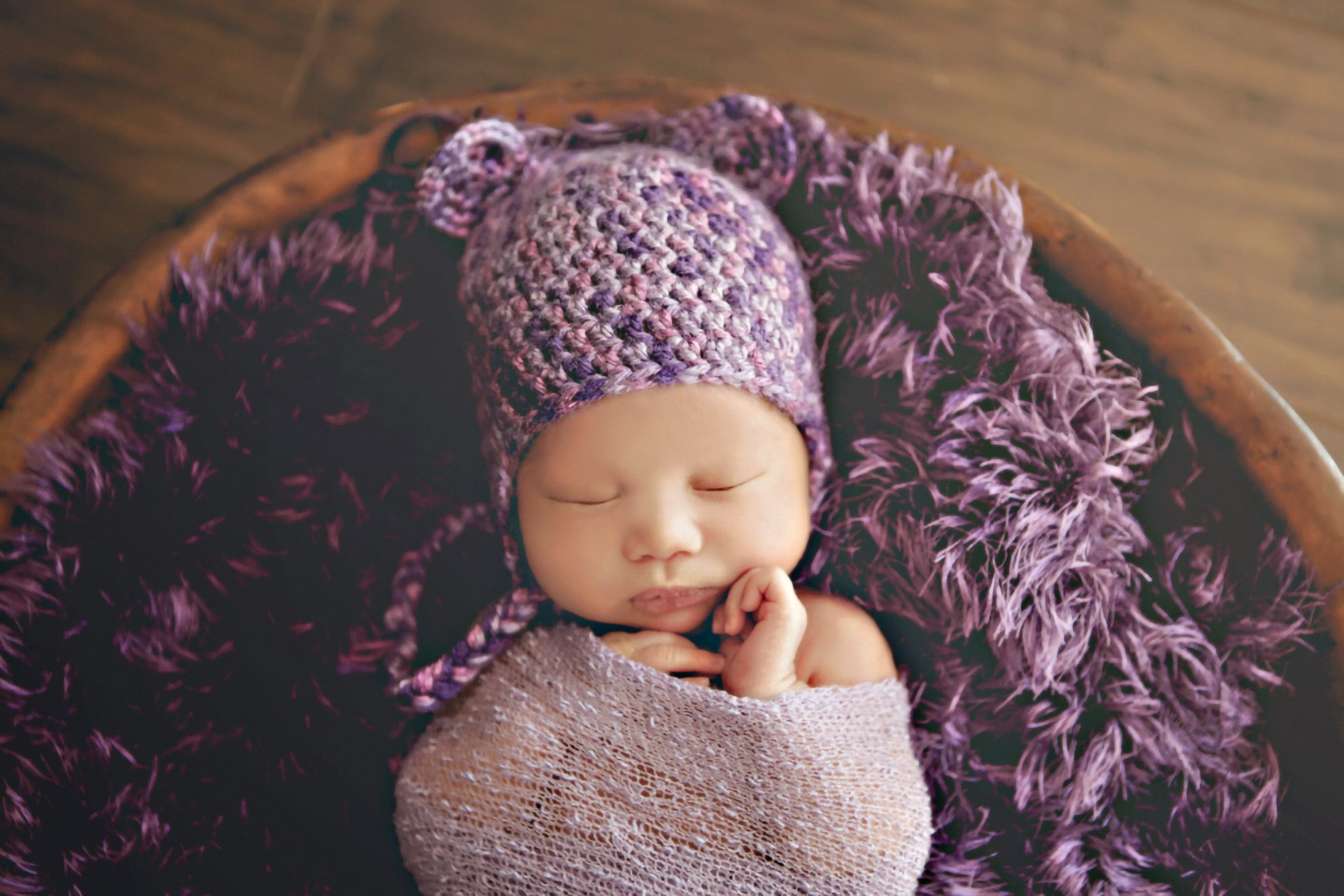 Newborn wrapped in purple blanket.