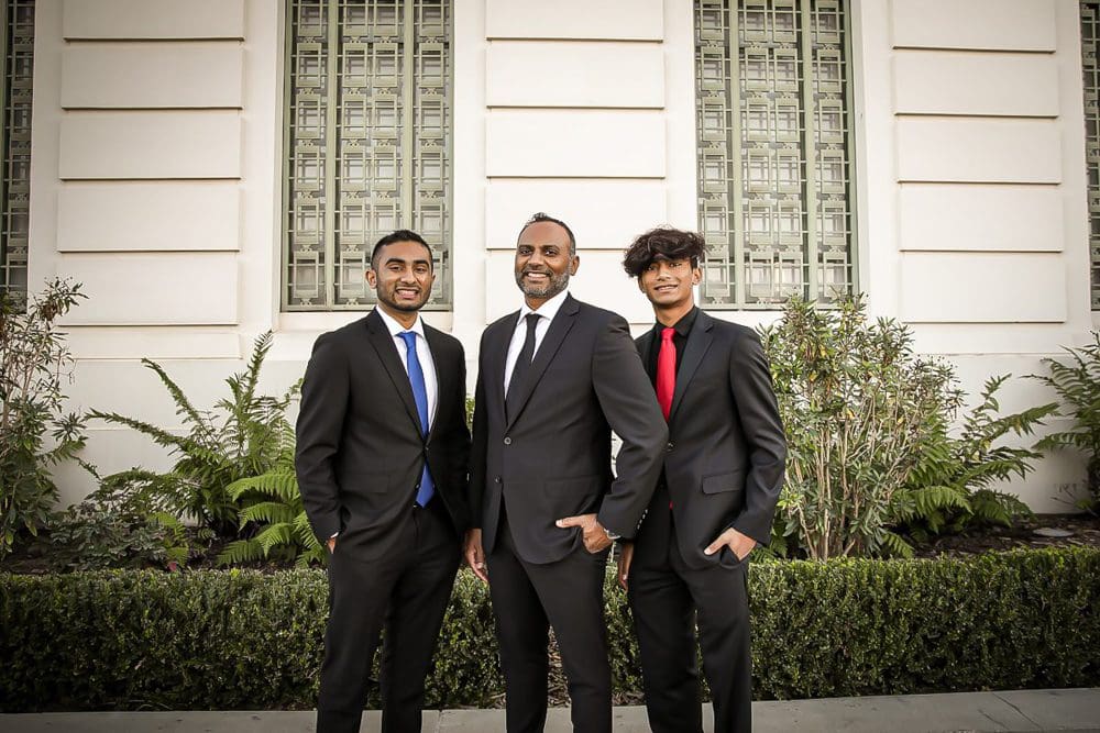 Three men in formal attire outdoors.