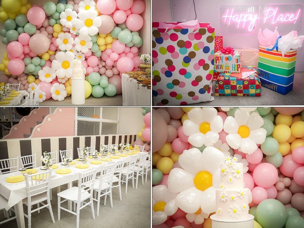 A pastel-themed kids birthday party photographer captures daisy balloon decorations, a cake topped with daisies, white chairs with yellow plates at a long table, and polka-dot-wrapped presents beneath a neon Happy Place! sign.