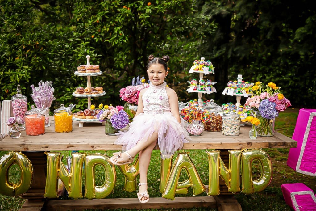Birthday girl in pink dress at colorful outdoor candy table