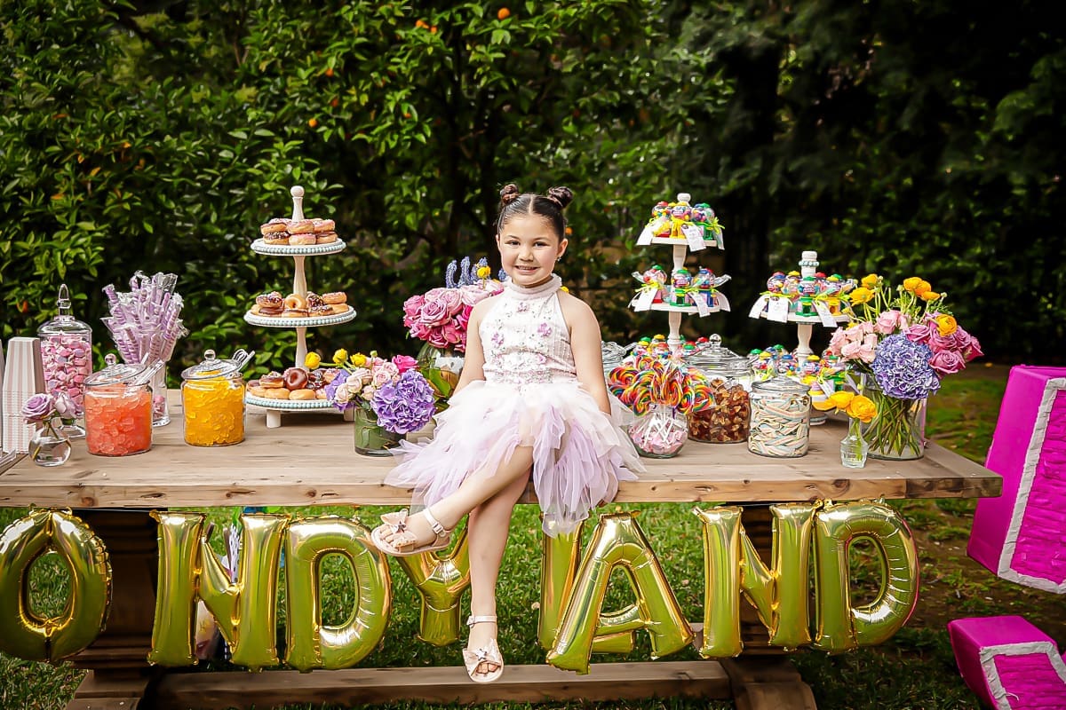Birthday girl in pink dress at colorful outdoor candy table