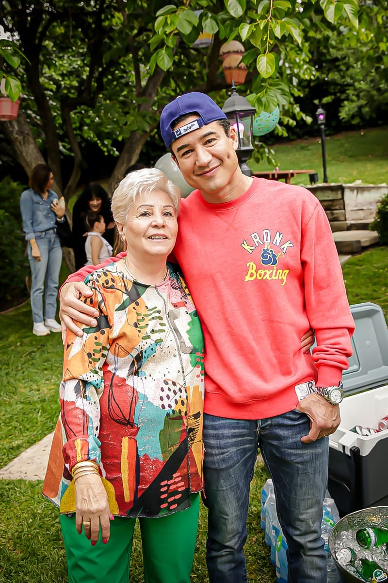 Smiling man in pink sweatshirt and older woman hug at a backyard birthday.